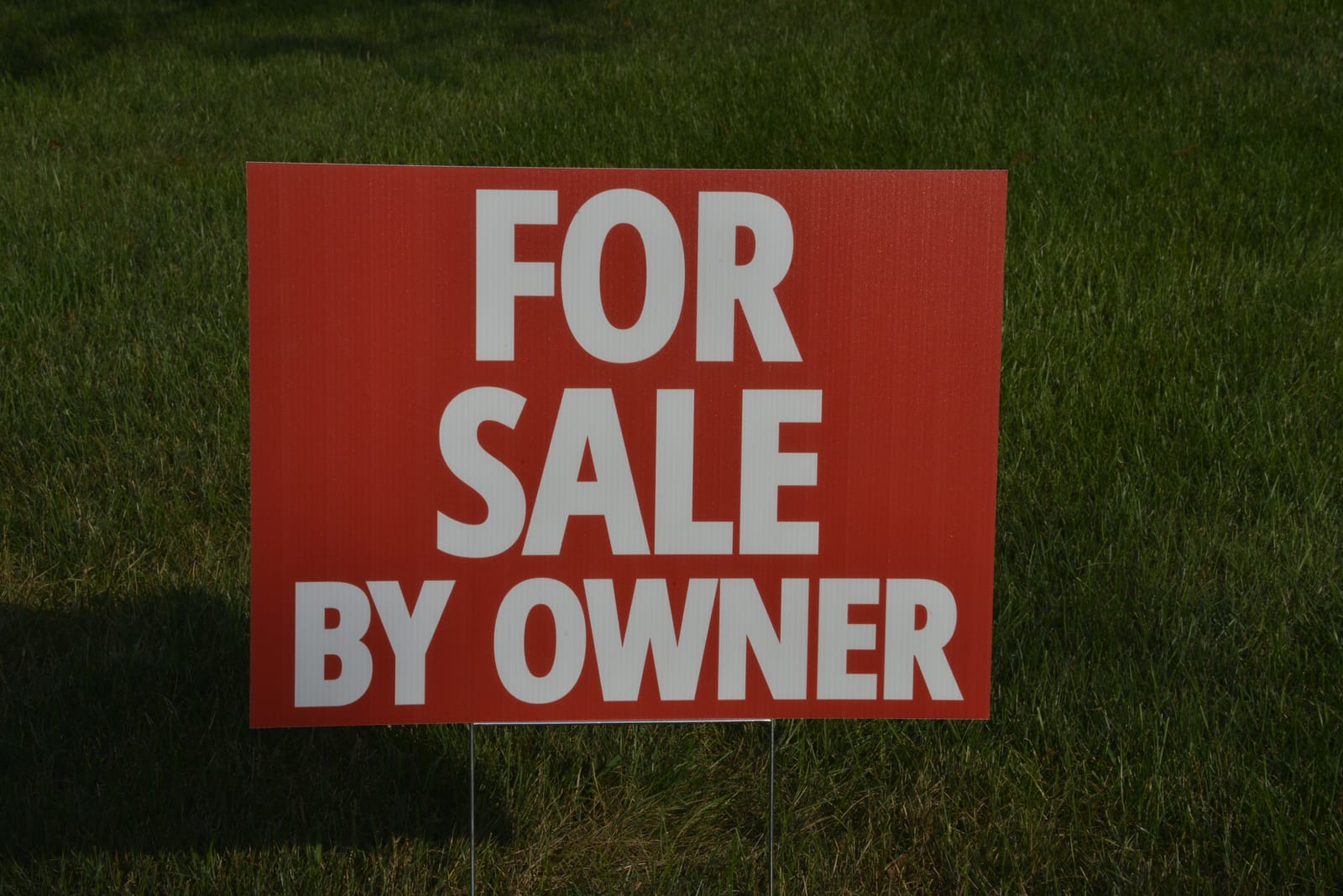 Red "For Sale By Owner" yard sign printed by Franklin Printing, staked in a lawn